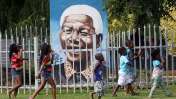 Un grupo de niños juegan  en un parque ubicado en Soweto que tiene una fotografía del líder Nelson Mandela quien se está recuperando de una operación.