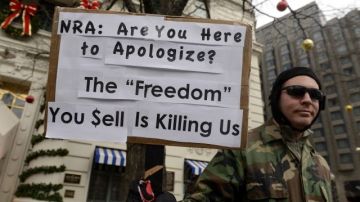Un hombre sostiene un cartel en el que se lee "Asociación del Rifle: ¿están aquí para disculparse? La 'libertad' que venden nos está matando" donde el vicepresidente ejecutivo de la Asociación Nacional del Rifle (NRA) de EE.UU., Wayne LaPierre, comparece ante la prensa en Washington DC, Estados Unidos.