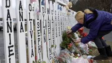 Una mujer colocaba ayer viernes un ramo de flores en una valla en la que están inscritos los nombres de las víctimas asesinadas en la Escuela Primaria Sandy Hook de Newtown, Connecticut.
