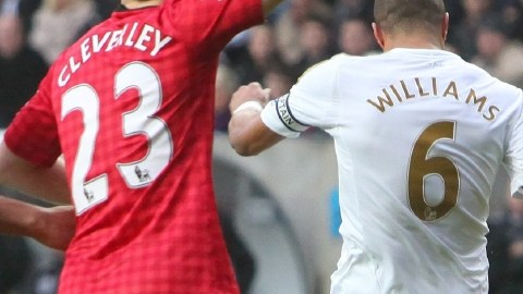 Ashley Williams patea el balón sobre la cabeza de  Van Persie.