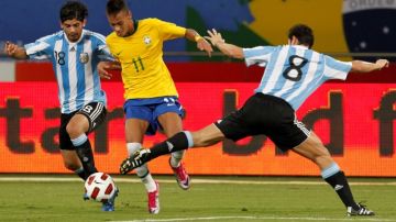 El astro brasileño Neymar intenta eludir la marca de los argentinos Javier Zanetti (8) y Ever Banegas en un partido amistoso entre los dos colosos sudamericanos. Ahora los directivos del Santos pretenden  juntarlo con Robinho.
