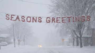 Un letrero de "Felices Fiestas" es cubierto por la nieve en una calle de Beaver Dam, estado de Wisconsin (EEUU).