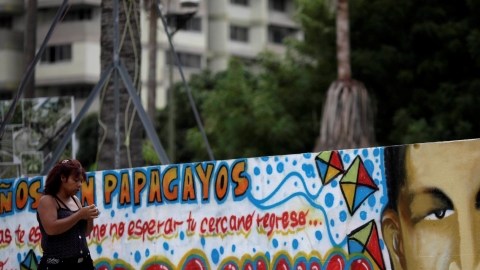 En el último día del año, una mujer pasa por un mural del presidente Hugo Chávez pintado en una calle de Caracas.