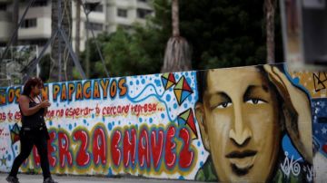 En el último día del año, una mujer pasa por un mural del presidente Hugo Chávez pintado en una calle de Caracas.