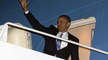 Obama saluda desde el avión que lo llevará a Honolulu en la base militar Andrews Air Force Base, Maryland.
