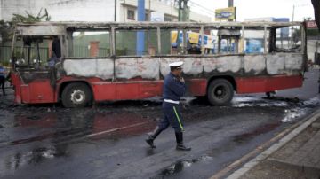 Un policía resguarda el lugar donde un autobús de transporte público fue incendiado hoy en la ciudad de Guatemala.