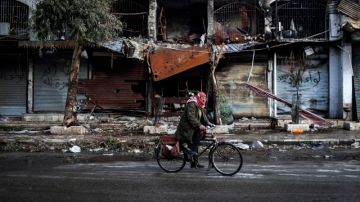 Un sirio cruza en bicicleta los edificios destrozados por los bombardeos que se han registrado en la ciudad de Aleppo.