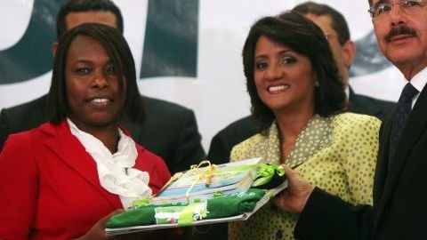 El presidente dominicano Danilo Medina, la primera dama, Cándida Montilla (c) y la voluntaria Feneida René, durante la entrega de un material didáctico.