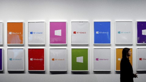 Una mujer permanece de pie al lado de unos cuadros con el logotipo de Windows 8 durante el lanzamiento nuevo sistema operativo de Microsoft.