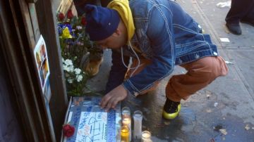 Una persona no identificada escribe un mensaje en una pancarta frente altar donde cayó abatido el joven Raphael Ward (abajo).