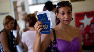Una mujer muestra dos pasaportes cubanos en una oficina regional de la Dirección de Inmigración y Extranjería en La Habana.