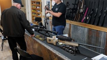 El vendedor de una tienda en Texas muestra a un cliente diferentes rifles de asalto, mientras se debate un mayor control.