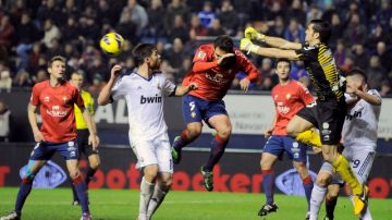 El portero de Osasuna Andrés Fernández rechaza el balón ante la presencia de Xavi Alonso y su compañero de equipo Manuel Ortiz. Real Madrid intentará ahora ganar la Copa del Rey pero tiene un duro rival en el Valencia.