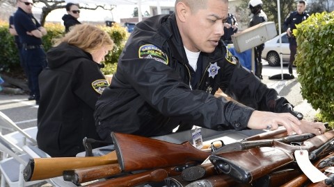 Un oficial revisa los rifles entregados durante un programa de intercambio de armas, al tiempo en que crece el apoyo a un mayor control.