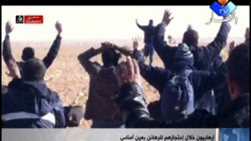 En esta imagen tomada de un video, un grupo de personas, que se cree que son rehenes, están de rodillas en la arena con sus manos alzadas en un lugar desconocido en Argelia.