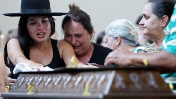 Familiares lloran sobre uno de los ataudes que fueron colocados en un gimnasio a donde llevaron a la víctimas para su identificación.