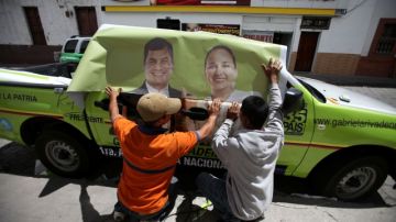 Miembros de Solución Publicitaria cubren una camioneta con publicidad de Gabriela Rivadeneira y Rafael Correa, candidatos de Alianza País, lista 35.