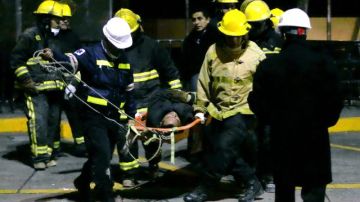 Bomberos evacúan a un rescatista herido durante los labores de rescate en el sitio de la explosión en la sede de la paraestatal Petróleos Mexicanos.