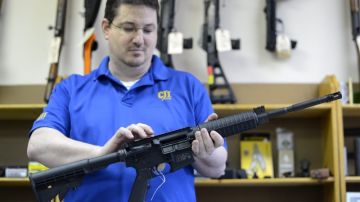 El  propietario de una armería sostiene un rifle semiautomático de asalto MP15, en su negocio en Tucker, Georgia.