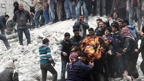 Sirios levantan un cadáver después que  un ataque aéreo de fuerzas del gobierno el domingo al barrio de Ansari.