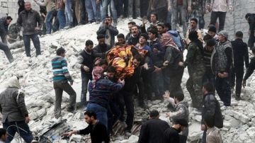 Sirios levantan un cadáver después que  un ataque aéreo de fuerzas del gobierno el domingo al barrio de Ansari.
