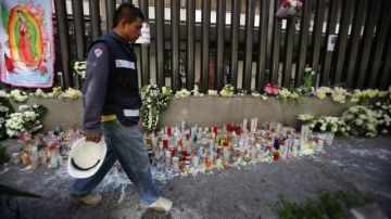 Un hombre camina  frente a decenas de velas y flores puestas ante la sede central de Pemex, para honrar a los muertos en la explosión del jueves pasado.