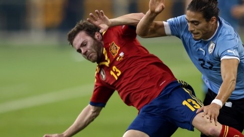 El español Juan Mata (izq.) pelea un balón con el uruguayo  Martín Cáceres en el encuentro de ayer que se celebró  en Qatar.