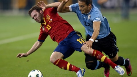 El español Juan Mata (izq.) pelea un balón con el uruguayo Martín Cáceres en el encuentro de ayer que se celebró en Qatar.