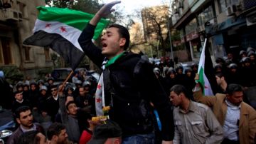 Manifestantes ondean la bandera  siria para protestar  por la visita del presidente de Irán, Mahmud Ahmadineyad, enfrente de la embajada iraní de El Cairo, Egipto.