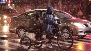 En plena nevada, este conductor de bicitaxi transporta a un cliente en Manhattan.