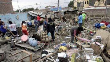 Miembros de una familia tratan de recuperar sus pertenencias entre los escombros de su casa, que sufrió los embates de las fuertes lluvias.