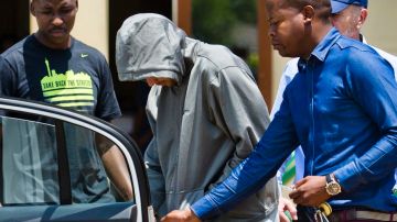El atleta sudafricano Oscar Pistorius se cubrió hoy cuando agentes de la policía lo trasladaron de su casa a otro lugar.