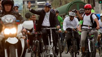 El presidente Rafael Correa de Ecuador, saluda a sus simpatizantes mientras hace un recorrido en moto en la ciudad de Quito.