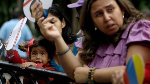 Una seguidora de Hugo Chávez se muestra pensativa en Caracas, mientras en Nueva York no hubo sreacciones alentadoras por el regreso del mandatario.