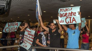Manifestantes que rechazan la visita al país de la disidente cubana Yoani Sánchez, sostienen carteles en el aeropuerto internacional Guararapes en Recife.