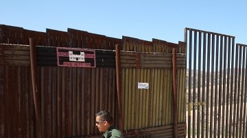 U.S. Border Patrol agent Santos Flores walks in front of the old border fence, back left, where it meets a five mile section of new border fence  at the border Thursday, June 19, 2008, in Nogales, Ariz. A U.S. Supreme Court decision paving the way for a 670-mile federal fence along the U.S.-Mexico border draws swift criticism from environmentalists, who promise to make another legal stand in Texas. (AP Photo/Ross D. Franklin)
