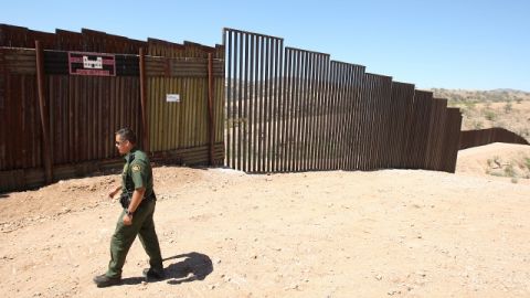 U.S. Border Patrol agent Santos Flores walks in front of the old border fence, back left, where it meets a five mile section of new border fence at the border Thursday, June 19, 2008, in Nogales, Ariz. A U.S. Supreme Court decision paving the way for a 670-mile federal fence along the U.S.-Mexico border draws swift criticism from environmentalists, who promise to make another legal stand in Texas. (AP Photo/Ross D. Franklin)