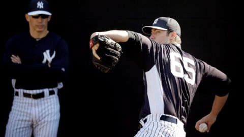Phil Hughes (der.) realiza un lanzamiento en el bullpen ante la mirada del manager de los Yankees,  Joe Girardi.