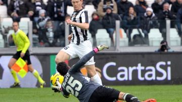 El defensor suizo Stephan Lichsteiner (arriba) de Juventus, supera al arquero del Sienna para convertir el primer tanto del líder italiano, que se impuso por 3-0.