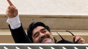 El exfutbolista argentino saluda a unos aficionados desde el balcón de su hotel en Nápoles, Italia, hoy martes 26 de febrero de 2013.