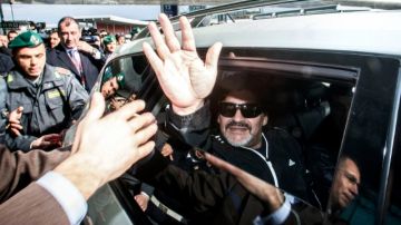 Diego Armando Maradona saluda a los aficionados que lo esperaban ayer a su llegada ayer al aeropuerto de Roma.