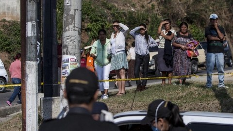 Agentes de la Policía Nacional Civil retiran  en un barrio popular del norte de la capital, el cuerpo de un taxista que fue presuntamente asesinado por un niño.