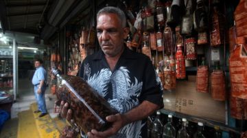 Mario, vendedor desde hace 30 años, muestra una botella de Mamajuana, en el Mercado Modelo, en Santo Domingo.