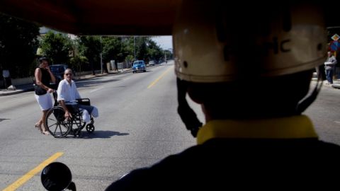 Un hombre en silla de ruedas trata de cruzar una peligrosa calle en La Habana.