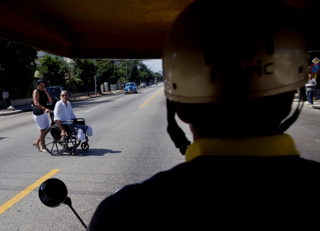 Un hombre en silla de ruedas trata de cruzar una peligrosa calle en La Habana.