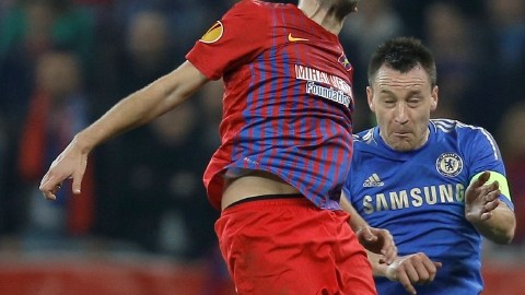 John Terry, del Chelsea, salta atrás del jugador del  Steaua de Bucarest,  Raul Rusescu,  en el juego de ayer celebrado en el National Arena.
