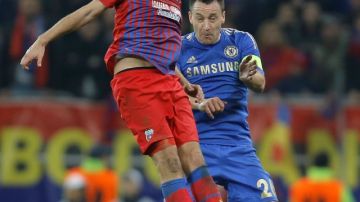 John Terry, del Chelsea, salta atrás del jugador del  Steaua de Bucarest,  Raul Rusescu,  en el juego de ayer celebrado en el National Arena.
