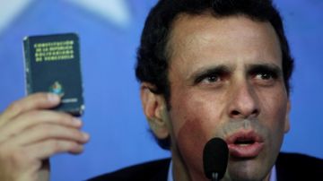Opposition leader Henrique Capriles holds up a miniature copy of Venezuela's Constitution as he speaks during a press conference in Caracas, Venezuela, Friday, March 8, 2013. Capriles called Vice President Nicolas Maduro a bold-faced liar and accuses him of using Hugo Chavez's funeral to campaign for the presidency. (AP Photo/Rodrigo Abd)
