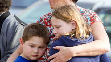 Una mujer no identificada y sus hijos visitan el sitio del accidente  que causó la muerte de seis jóvenes, en Park Ave.