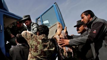 Soldados afganos retiran el cadáver de uno de los pasajeros de un camión, contra el que fuerzas de los EEUU abrieron fuego ayer  entre Kabul y Bagram.